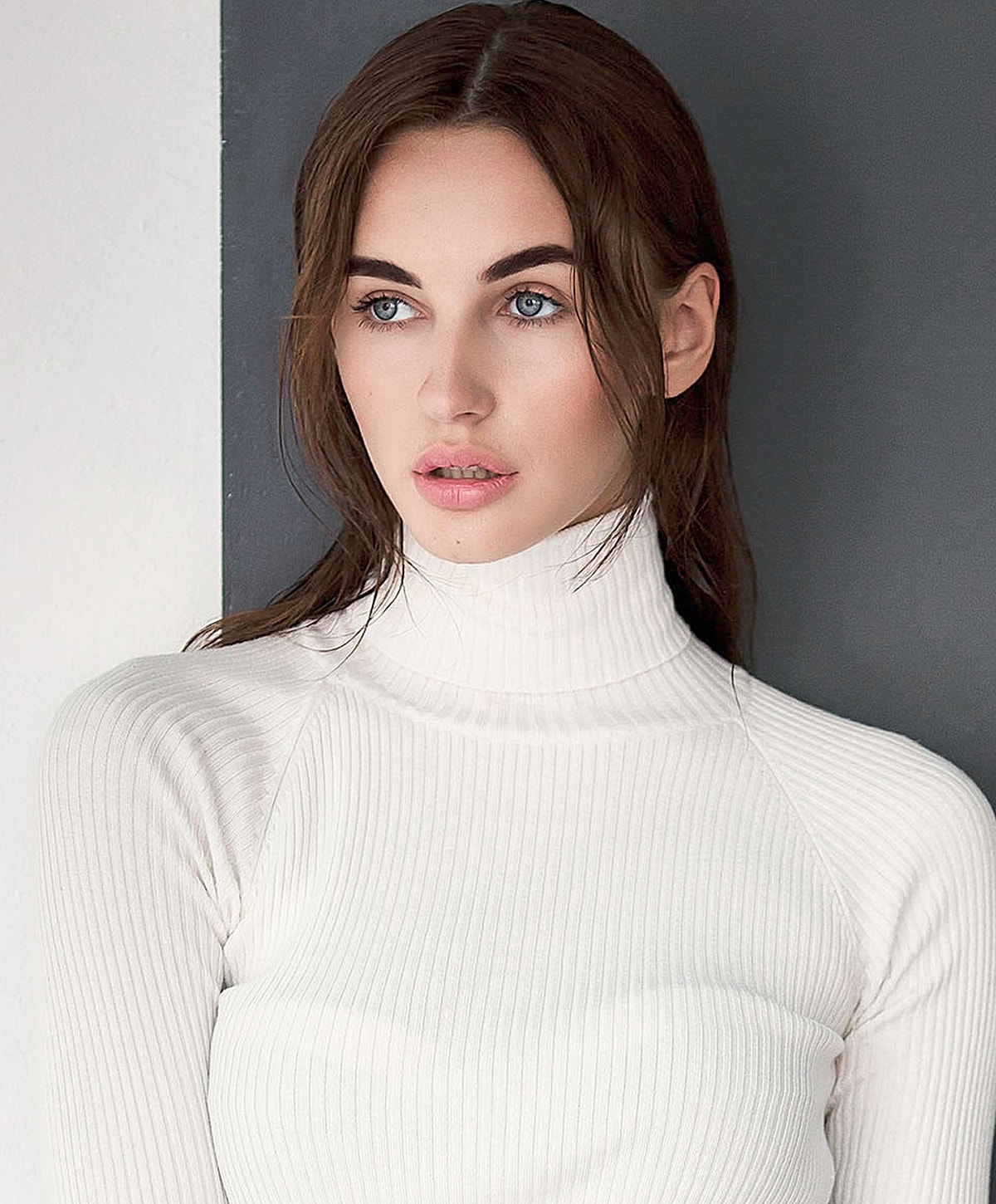 Model in white turtleneck sweater with casual expression.