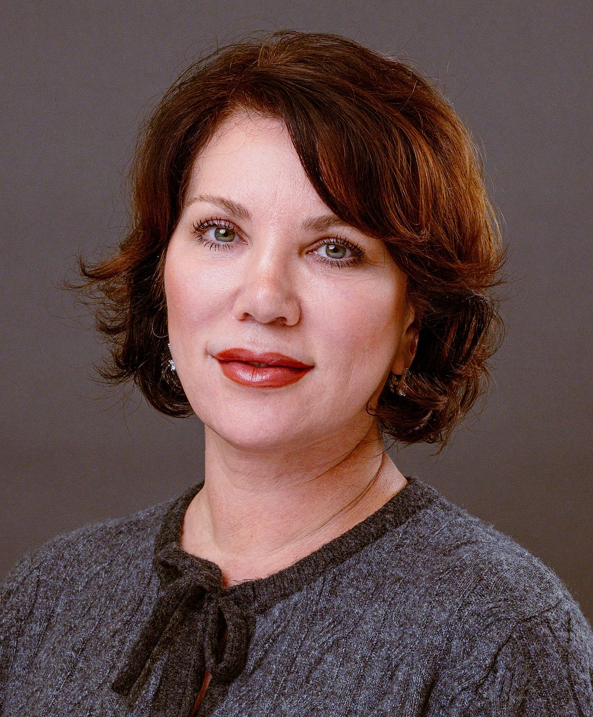 Woman with short brown hair and gray sweater.