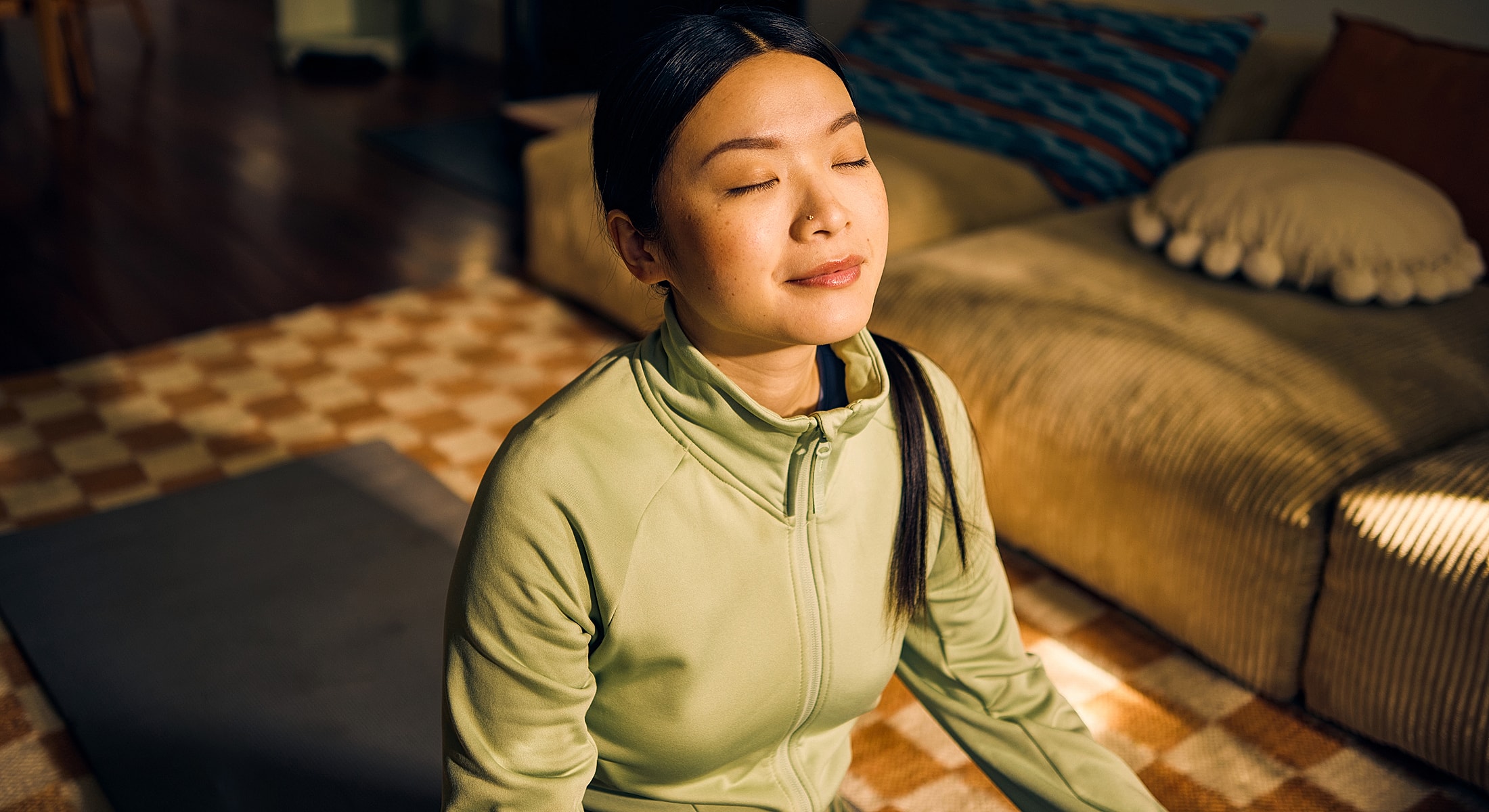 Woman meditating in a cozy indoor setting.