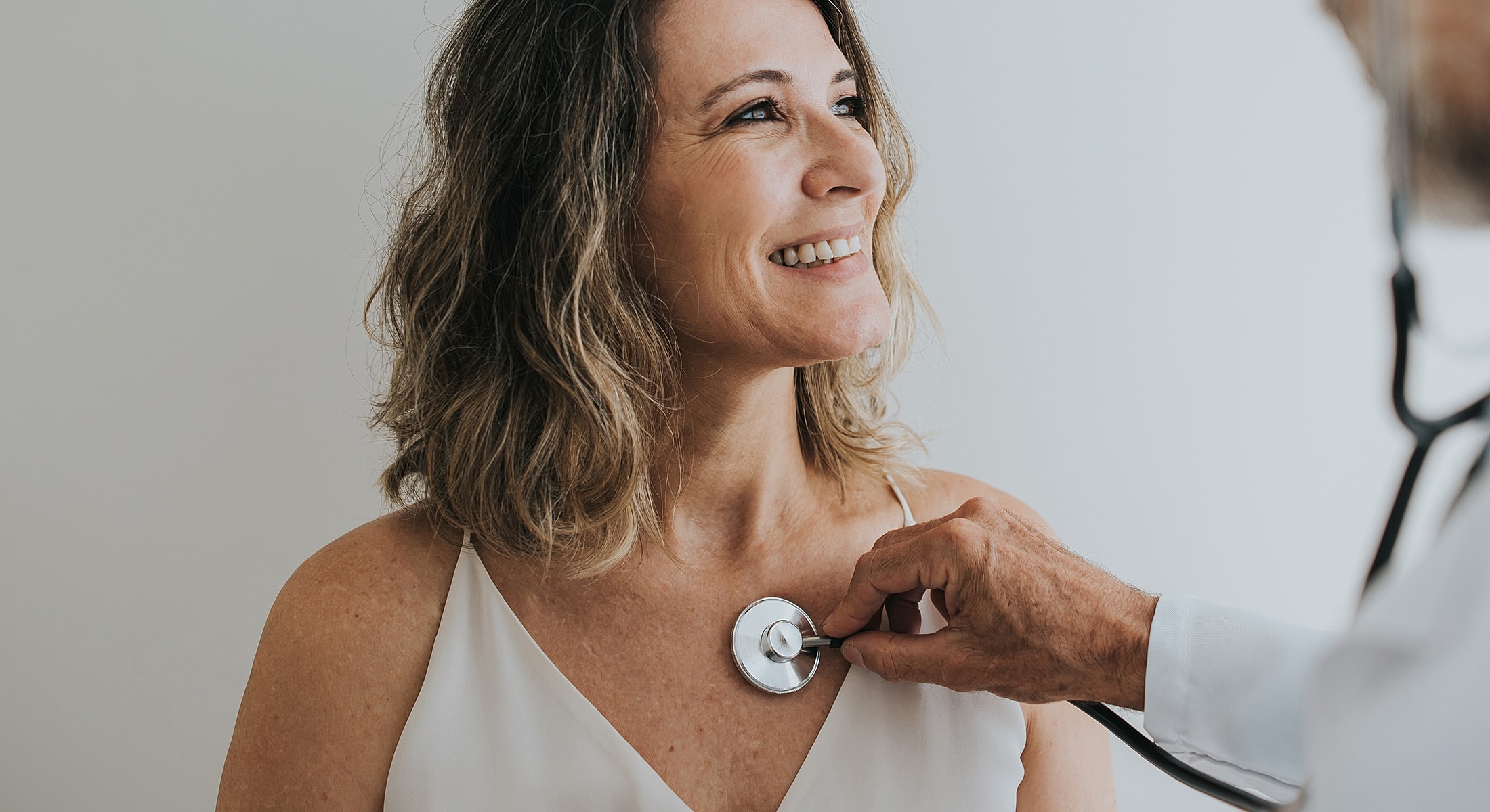 Doctor examining patient with stethoscope smiling.